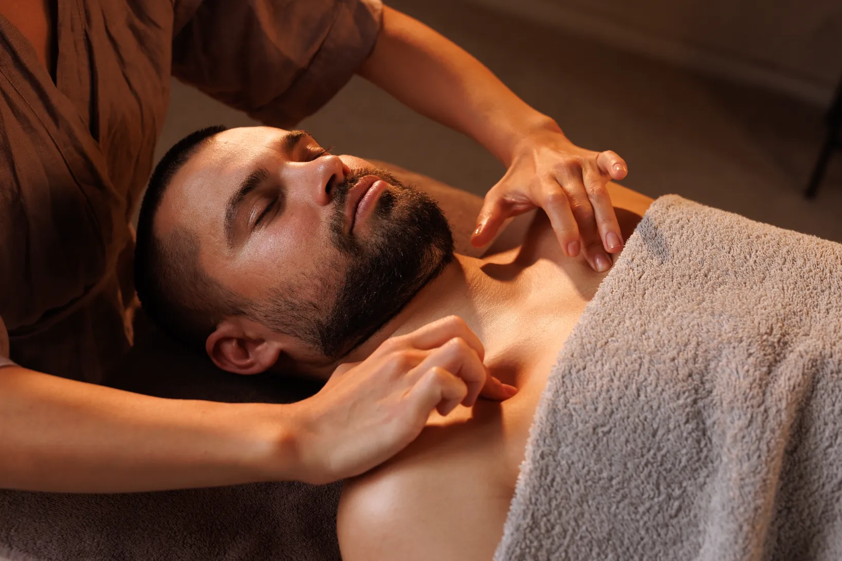 A guy getting his chest part treated by massaging it in a spa.