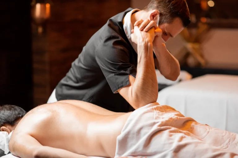 A man gently massaging the back part of the client in a spa.